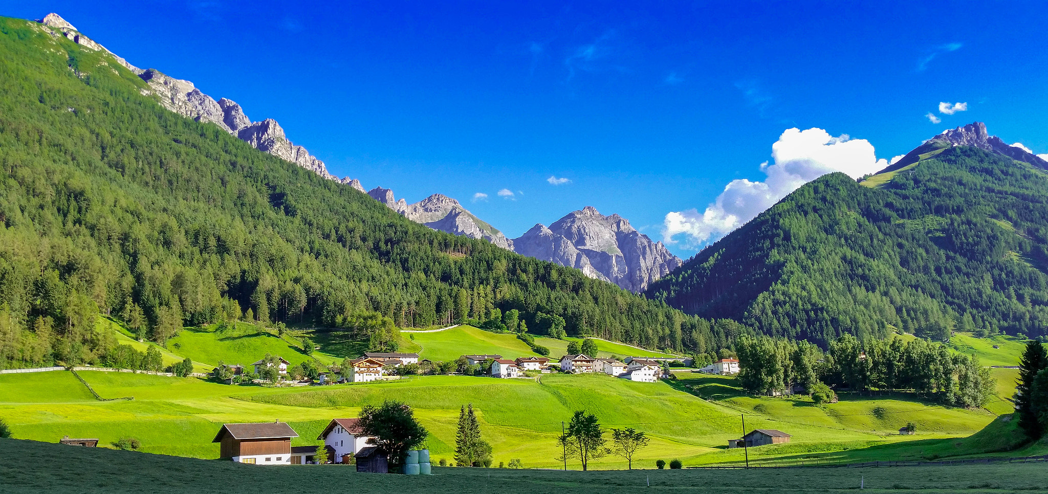 Sunlit green valley and mountain peaks in the Alps